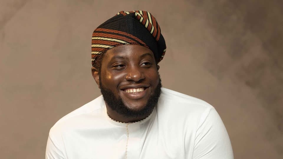 A headshot of Oluwatumininu Oyetayo. He is grinning at the camera.